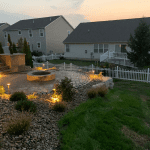 A backyard patio with a fire pit and landscaping.